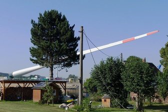 Windkraftanlagen für Voigtsdorf: Anwohner im Erzgebirge wegen Transport zeitweise ohne Strom - Bevor der Schwerlasttransport mit dem rund 80 Meter langen Rotorblatt ankommt, ist an diesem Strommast (Mitte) nahe der Heinzebank die Stromleitung vorübergehend gekappt worden.