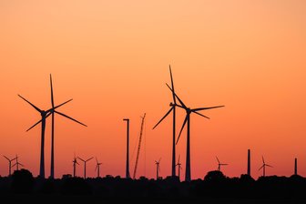 Windkraftmoratorium in Mittelsachsen: Geht das überhaupt? - Symbolbild: Der Morgenhimmel leuchtet über einer Landschaft mit Windenergieanlagen.