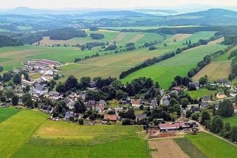 Windkraftprojekt im Erzgebirge: AfD-Initiative findet Mehrheit im Stadtrat - Ein großer Teil von Hermannsdorf aus der Luft. Hinten, etwa in der Mitte, ist der Bereich zu sehen, auf dem möglicherweise Windräder errichtet werden könnten.