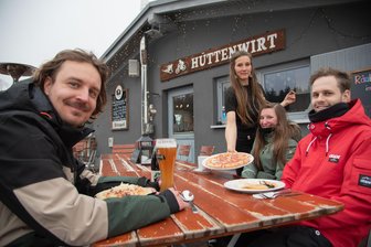 „Wir wurden regelrecht überrannt“: Wie der Hüttenwirt in Schöneck den Gästeansturm meistert - Nancy Lenke (Mitte) gehört zum neuen Team im Hüttenwirt. Die Gastro-Einrichtung verzeichnet einen Gästeaufschwung. Maximilian Heidowitzsch (links), Jasmin Jacob und Silas Strobel haben es sich dort schmecken lassen.
