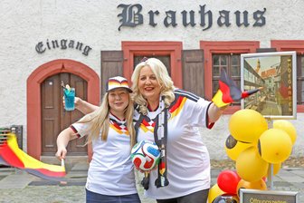 WM in Westsachsen: Hier können Fans am Sonntag gemeinsam das Deutschland-Spiel sehen - Einstimmung aufs erste WM-Spiel der DFB-Elf am Sonntagabend: Brauhaus-Inhaberin Anja Escher mit Tochter Ella, Deutschland-Fahne und einem Glas Curaçao im Domhof.