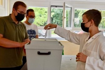 Wo Schüler ihre Stimme für eine Partei abgeben können - Achtklässler Collin Krönert (rechts) schlüpfte in der Pause des Chemieunterrichts zur Jugendwahl in Limbach-Oberfrohna an die Wahlurne, an der Lucas Schreckenbach (hinten) und Marvin Müller (vorn) vom Jugendbeirat auf die Schüler warteten.