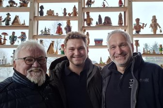 Wo Weihnachten nicht endet: Hier im Erzgebirge genießen Hunderte Räuchermännel ihren Ruhestand - Rolf Höfer sowie Florian und Lutz Kunze (von links) sind die Initiatoren des „Räuchermännelsruh 2.0“. Die auf der Terrasse befindliche Räuchermännelwand hinter ihnen wurde nach Lichtmess wieder abgebaut, Die Männel im Gastraum bleiben das Jahr über stehen.