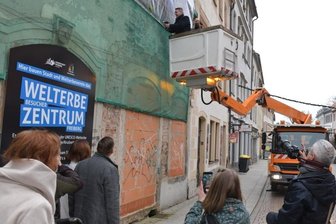 Worauf Innenstadthändler in Freiberg jetzt hoffen - Das Welterbezentrum in der Petersstraße soll auch mehr potenzielle Kunden für die Händler anlocken. Am 21. Dezember vorigen Jahres befestigte Oberbürgermeister Sven Krüger persönlich ein Werbebanner an der Ruine. Aktuell sind hinter der Fassade Handwerker zugange. 