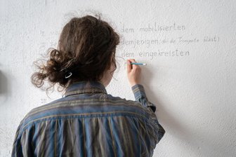 „Woraus wir gemacht sind“: Pochen-Ausstellung im Chemnitzer Wirkbau verbindet DDR und Ukraine-Krieg - Die ukrainische Künstlerin Dasha Chechushkova hat an die Wand geschrieben, wem sie ihr Werk widmet.