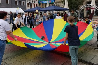 Wunderbar buntes Gewimmel: Zwickauer Straßenfest „EigenArt“ kommt gut an - Mitmach-Aktion des Gemeinnützigen Schulungszentrums für Sozialwesen Auerbach: Auf dem Schwungtuch wird ein Würfel belanciert.