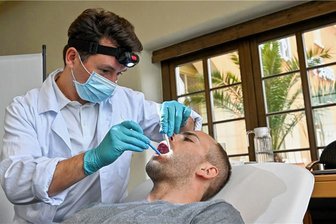 Zahnuntersuchung im Hotel: Warum wird den Limbach-Oberfrohnaern eine Woche lang in den Mund geschaut? - Zahnarzt Leonard Kohl untersucht die Zähne eines Probanden, der für die Teilnahme an der Studie zufällig ausgewählt wurde.