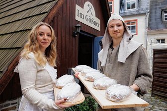 Zehn Wochen vor Weihnachten: Stollen aus dem Erzgebirge reifen im Besucherbergwerk - Stollenmädchen Marta Zimmermann und Verkaufsleiter Martin Seidler vom Unternehmen Annaberger Backwaren mit den Stollen, die ins Besucherbergwerk "Im Gößner" gebracht wurden. 