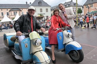 Zeitreise im Erzgebirge: Oldtimer ziehen bei Sommer-Oldies in Zwönitz die Blicke auf sich - Gunter und Heidi Weißbach sind mit ihren Berliner Rollern bei den „Erzgebirgs-Classics“ dabei gewesen – hier mit Moderator Silvio Zschage bei der Vorstellung der Fahrzeuge, die sich an der Oldtimer-Ausfahrt beteiligt haben.