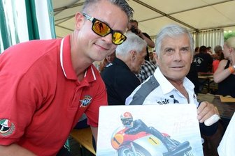 Zement als Puder: Heißes Rennen lässt Asphalt schmelzen - Matthias Hinkel aus Bad Schlema (links) mitten in der Glückseligkeit: Beim Dreieckrennen in Zschorlau nutzte der Motorsportfan seine Chance, um sich von Weltstar Giacomo Agostini ein Autogramm zu holen.