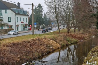 Zoff um Bachufer in St. Egidien: Streitbare Gemeinde will einen Konflikt beenden - Gegenüber der Sparkasse (links) hat die Gemeinde Parkplätze angelegt und in Richtung Bach Mutterboden aufgefüllt – laut Landratsamt ein Eingriff ins Überschwemmungsgebiet.
