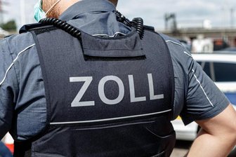 Ein Beamter trägt während seines Dienstes eine Schutzweste mit der Rückenaufschrift "Zoll".