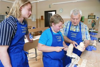 Zschopauer Schüler verdienen sich mit dem Schnitzmesser gute Noten - Unter Anleitung von Kevin Frevert (links) und Ullrich Zimmermann hat der elfjährige Sebastian Kramer im Schülerverein große Fortschritte als Schnitzer gemacht, aber auch der soziale Aspekt kommt nicht zu kurz.
