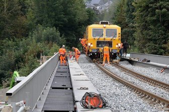 Züge der Erzgebirgsbahn rollen ab Mittwoch übers neue Viadukt in Schwarzenberg - Mit einer sogenannten Gleisstopfmaschine wurde der Schotter unter und neben den Gleisen verdichtet. Links im Bild sind Mitarbeiter des Unternehmens dabei, die Gangstege und Geländer auszurichten und zu befestigen.