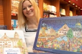 Zum Plauener Wimmelbuch gibt es jetzt ein passendes Puzzle - Sophie Gürtler vom Dachverband Stadtmarketing mit dem neuen Puzzle und dem Plauener Wimmelbuch.