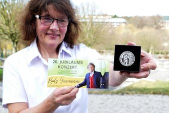 Zum Warmbader Jubiläum von Rudy Giovannini gibt es ein besonderes Geschenk - Neben der Eintrittskarte fürs 20. Warmbader Konzert von Rudy Giovannini präsentiert Mitarbeiterin Sabine Börner vom Kur- und Gesundheitszentrum auch die Jubiläumsmünze, die ab sofort erhältlich ist.
