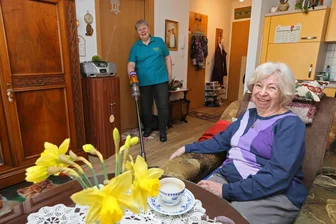 Zurück ins Leben: Wie Senioren in Zwickau durch Nachbarschaftshilfe wieder Anschluss finden - Gelebte Nachbarschaftshilfe im Verein: Rosmarie Schönerstedt (95) plaudert in ihrem Sessel mit Kerstin Lässig, die den Fußboden säubert.