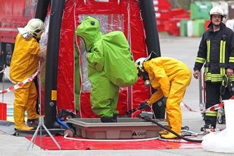 Schutzanzügen pumpen Feuerwehrmänner derzeit den Inhalt des Spezialbehälters um und reinigen anschließend den kontaminierten Laster
