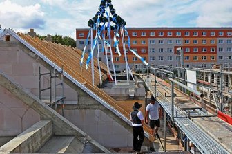 Zwickau-Eckersbach: Erst Plattenbauten, dann Reihenhäuser - Auch von den Fenstern der Plattenbauten aus wurde das Richtfest der Reihenhaussiedlung beobachtet. Dachdecker und Zimmerer warten am Dachstuhl auf den Richtspruch. 