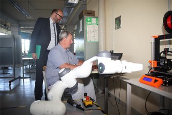 Zwickauer Berufsschule kooperiert mit Wirtschaft: Roboter „Panda“ soll Berufsausbildung sexy machen - Leichtbauroboter Panda (vorn) im Zusammenspiel mit einem 3D-Drucker. Wie das funktioniert, hat Fachleiter Ingolf Böhm am Dienstag Sachsens Kultusminister Christian Piwarz (links) am BSZ für Technik in Zwickau demonstriert.