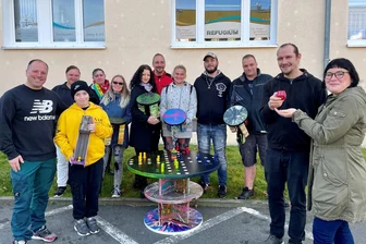Zwölf kreative Köpfe aus dem Erzgebirge knobeln an einem Spieltisch für große und kleine Leute - Diese Kursteilnehmer haben den Outdoor-Spieletisch entworfen und gebaut. Symbolisch übergab Matthias Hensel den roten Spielewürfel an Ina Heßelbarth (r.) vom Verein Refugium in Raschau.